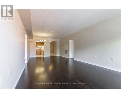 A spacious room with wooden floors and white walls, with a sign that reads "RE/MAX METROPOLITIC REALTY, Brokerage".