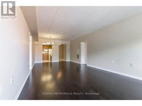 A spacious room with wooden floors and white walls, with a sign that reads "RE/MAX METROPOLITIC REALTY, Brokerage".