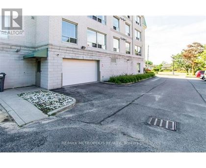 A building with a closed garage door and a sign that says REMAX METROPOLITIS REALTOR.