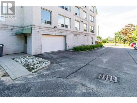 A building with a closed garage door and a sign that says REMAX METROPOLITIS REALTOR.