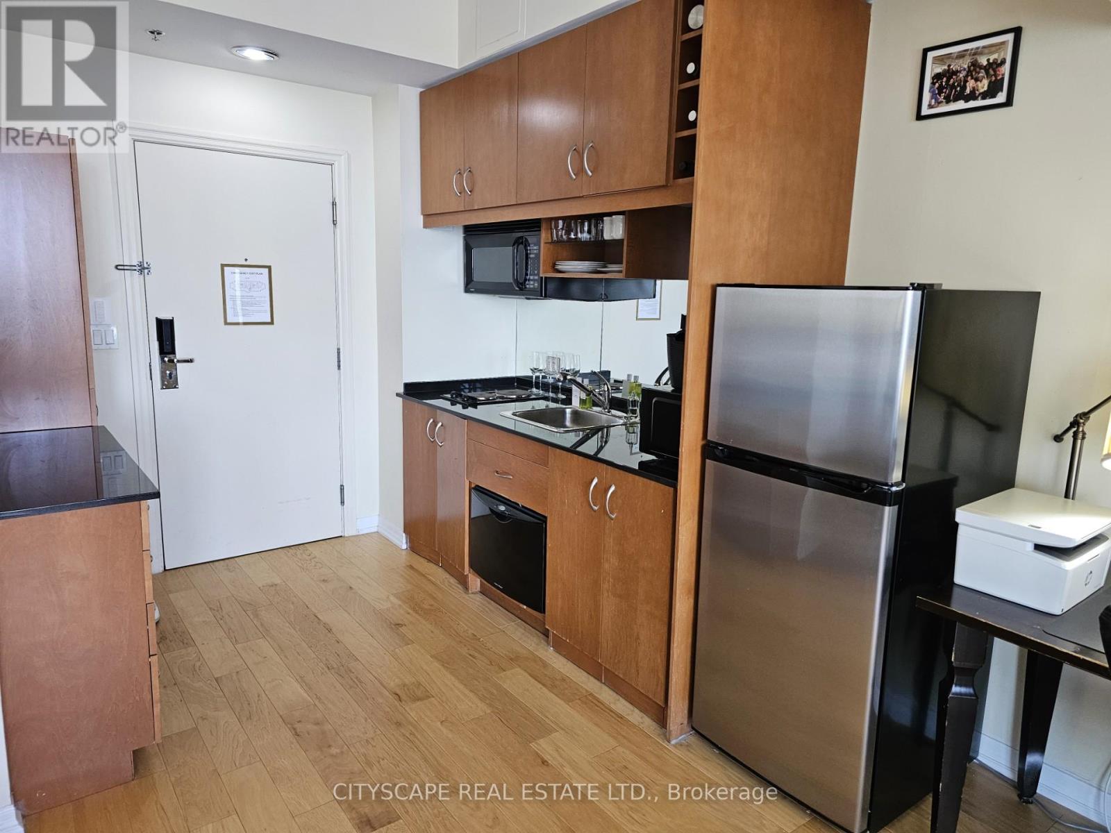 A kitchen with wooden cabinets and a stainless steel refrigerator.