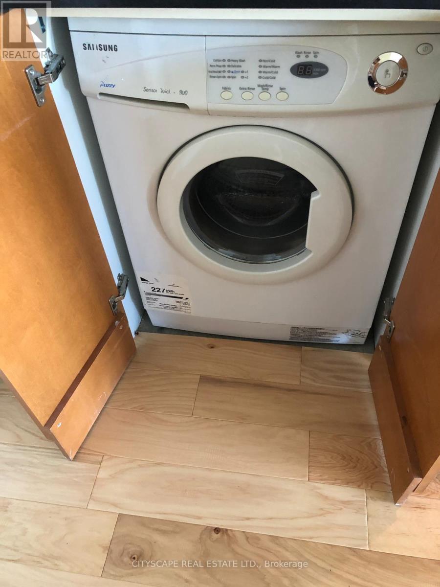 A Samsung washing machine is in a small space with wood flooring.