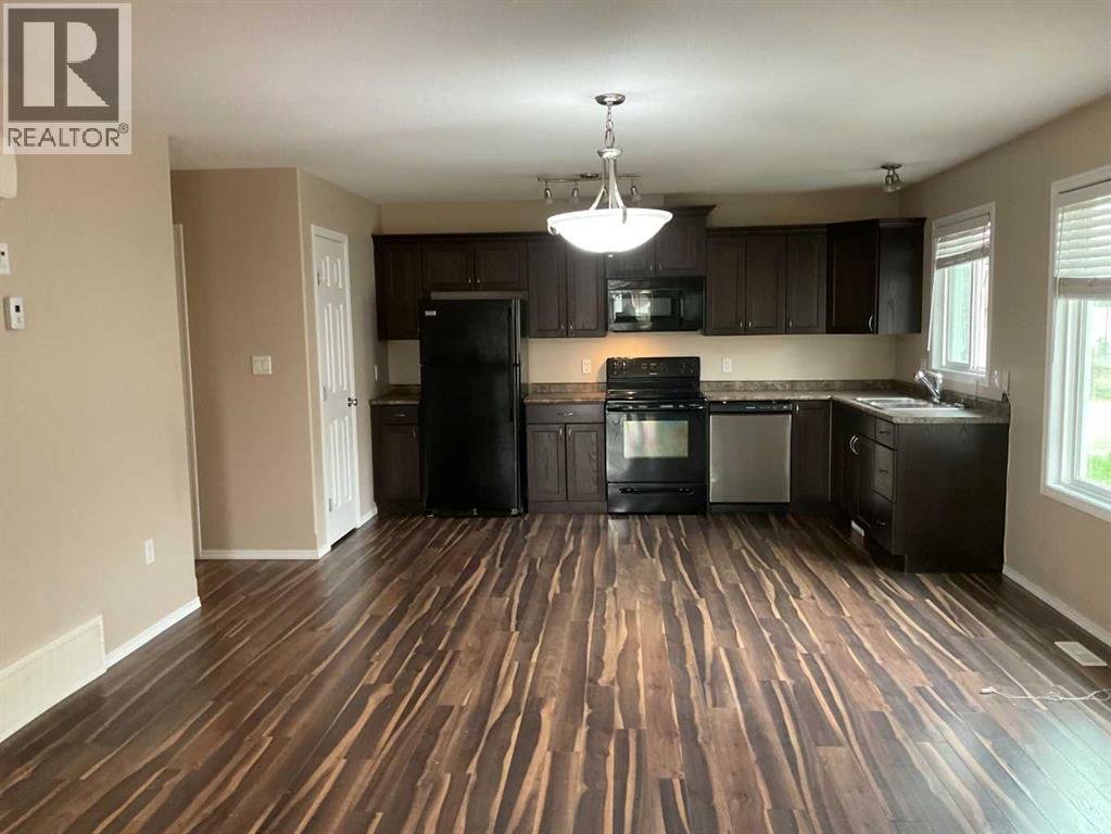 A kitchen with wood flooring and black appliances.