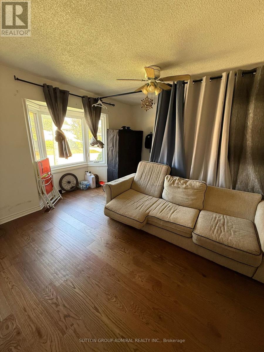 A living room with a beige couch and a fan.