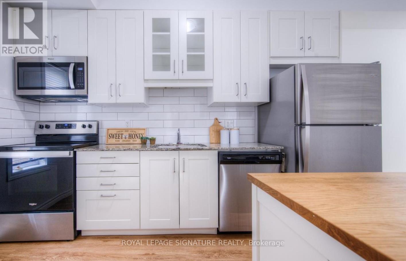 A kitchen with white cabinets and a wooden counter top.