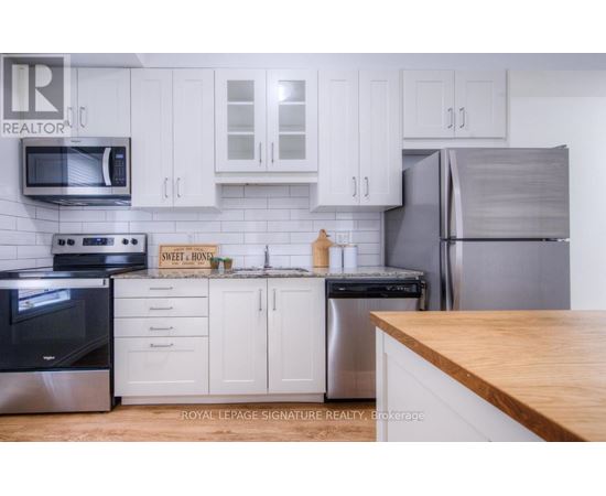 A kitchen with white cabinets and a wooden counter top.