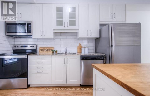 A kitchen with white cabinets and a wooden counter top.