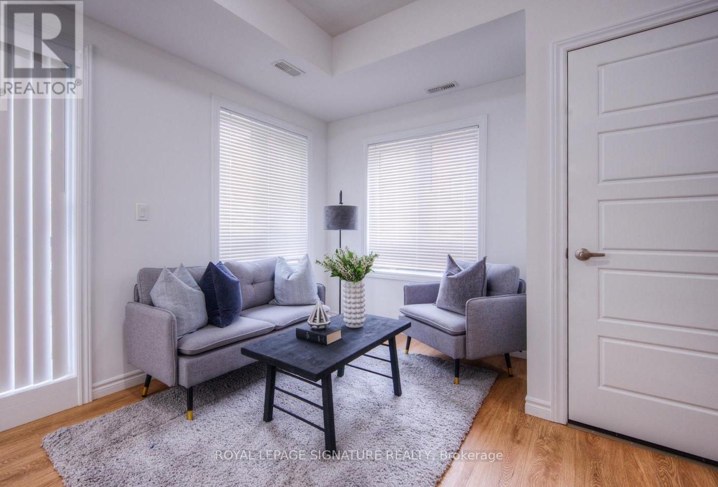 A living room with a grey couch, a black coffee table, and a grey armchair.