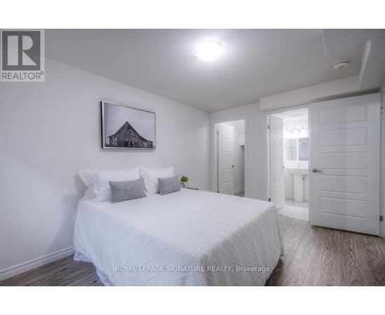 A bedroom with a bed, a picture on the wall, and a door leading to another room.
