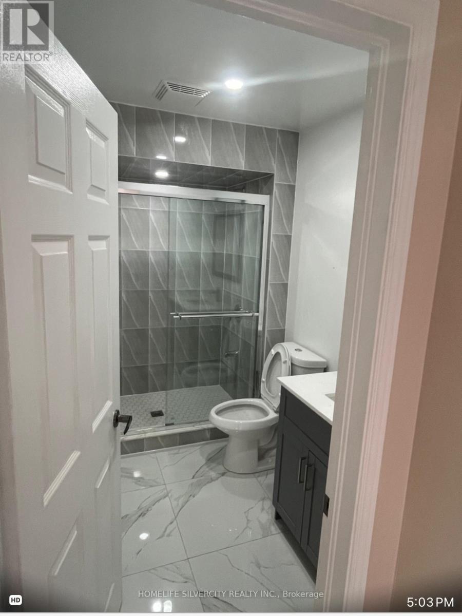 A bathroom with a glass shower door and a toilet.