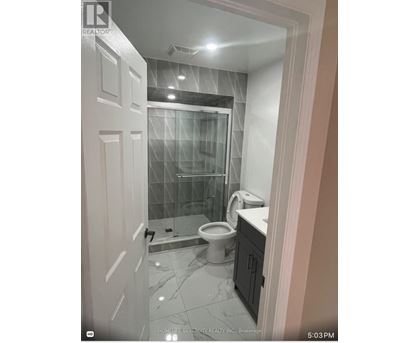 A bathroom with a glass shower door and a toilet.