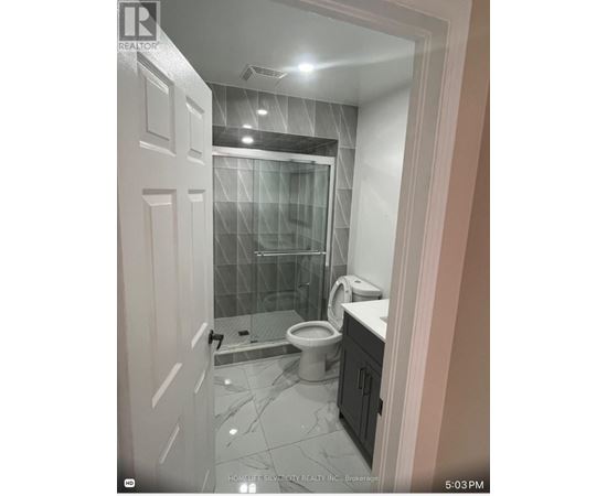 A bathroom with a glass shower door and a toilet.