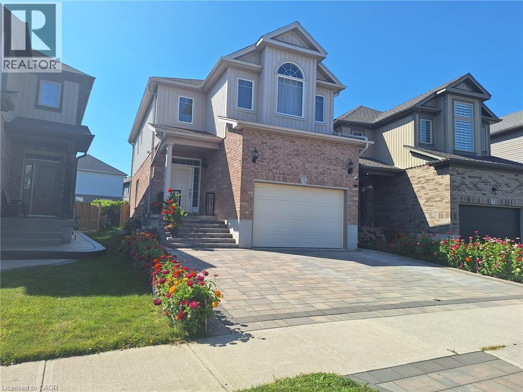 A house with a driveway and garage is surrounded by a well-kept lawn and flower beds.