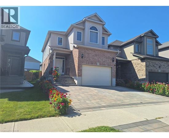 A house with a driveway and garage is surrounded by a well-kept lawn and flower beds.
