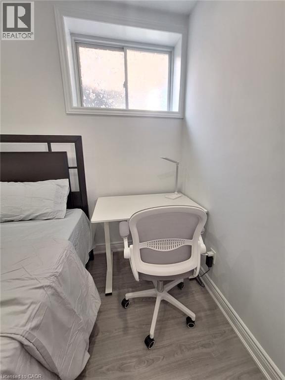 A white chair is in a white bedroom with a bed and a desk.