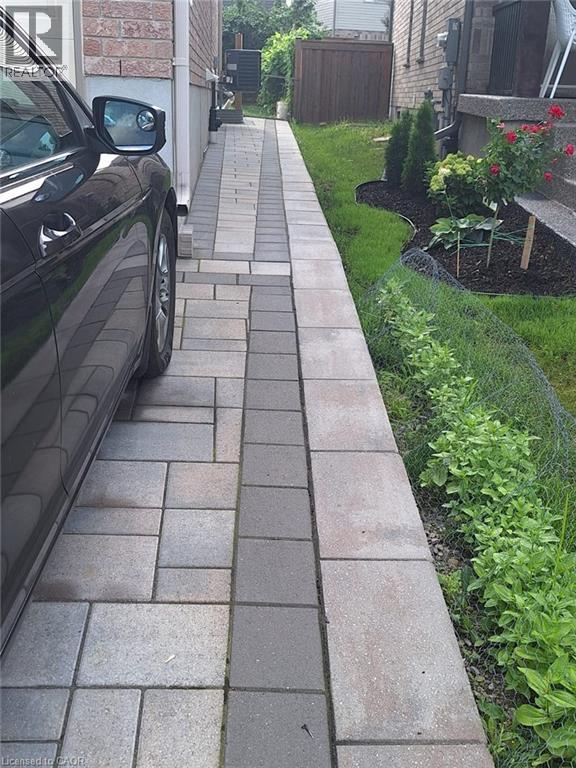 A black car is parked on a brick sidewalk.