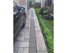 A black car is parked on a brick sidewalk.