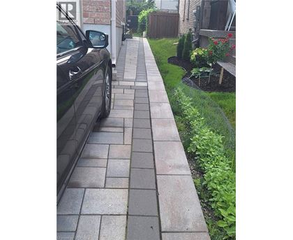 A black car is parked on a brick sidewalk.