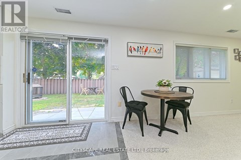 A dining room with a table and chairs and a painting on the wall.