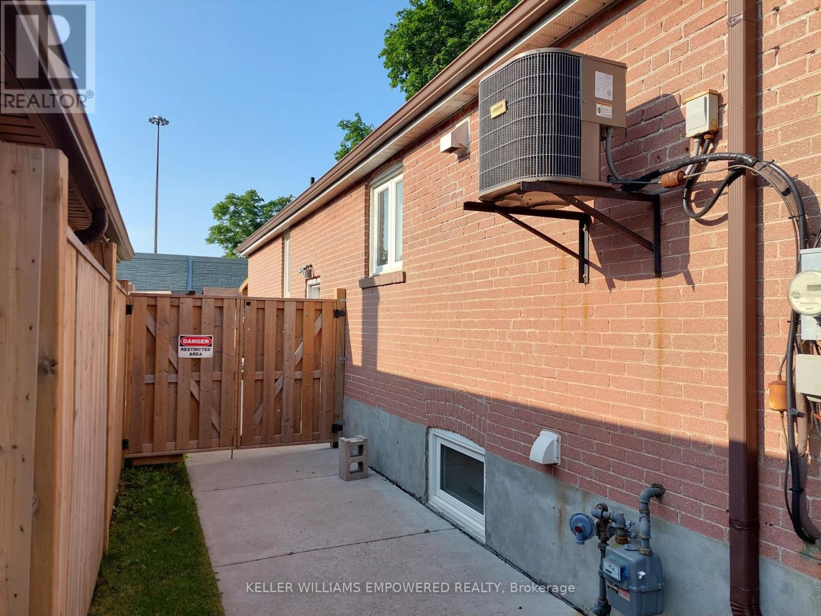 A red brick house with a wooden fence and a sign that says "No Trespassing".