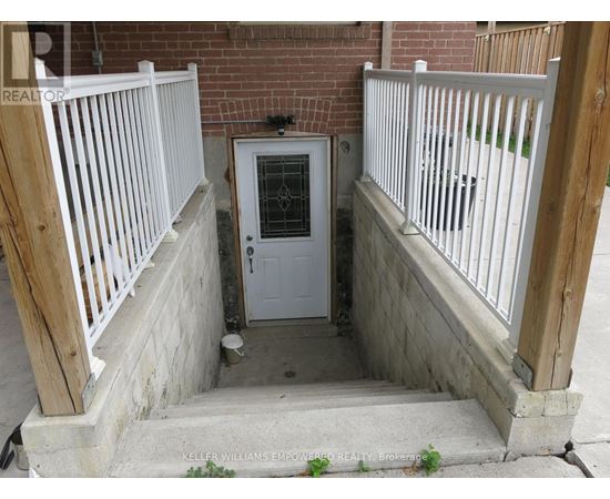 A white door with a glass window is in the middle of a concrete area with a wooden railing on either side.