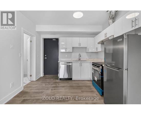 A kitchen with white cabinets and a black door.
