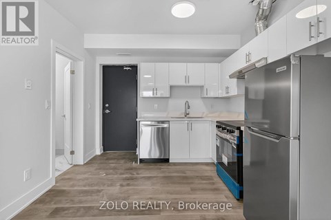 A kitchen with white cabinets and a black door.