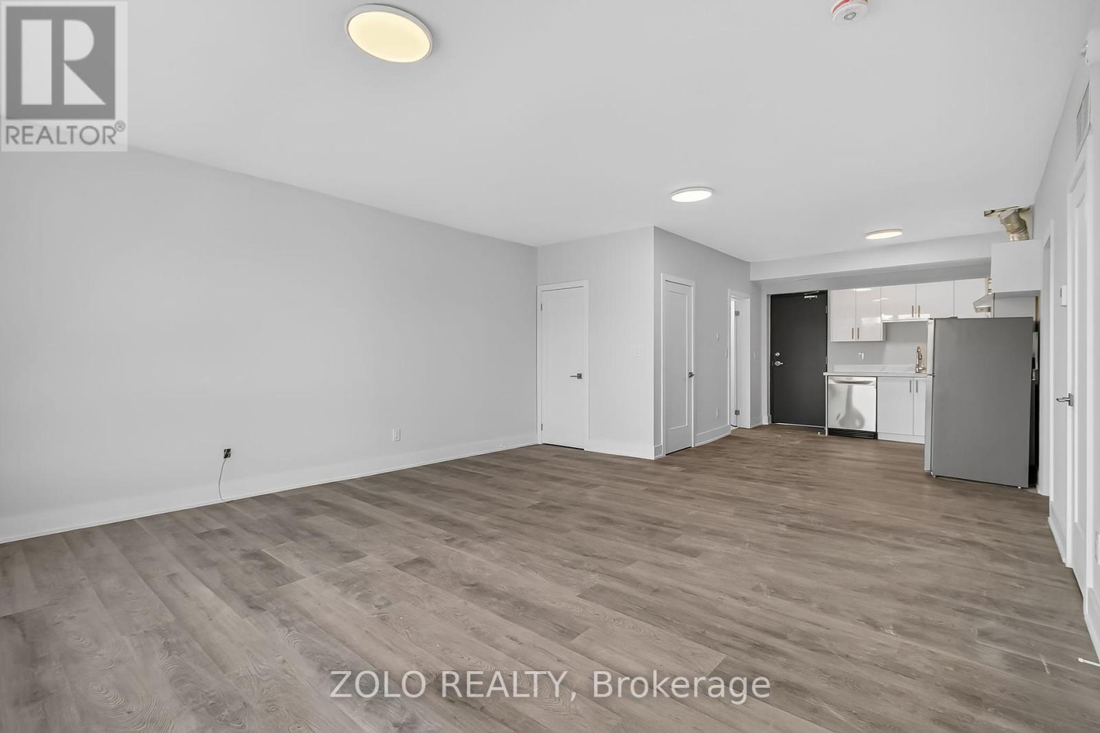 A spacious room with wooden flooring and white walls, with a doorway leading to another room.