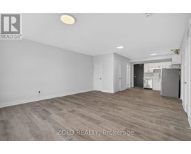 A spacious room with wooden flooring and white walls, with a doorway leading to another room.