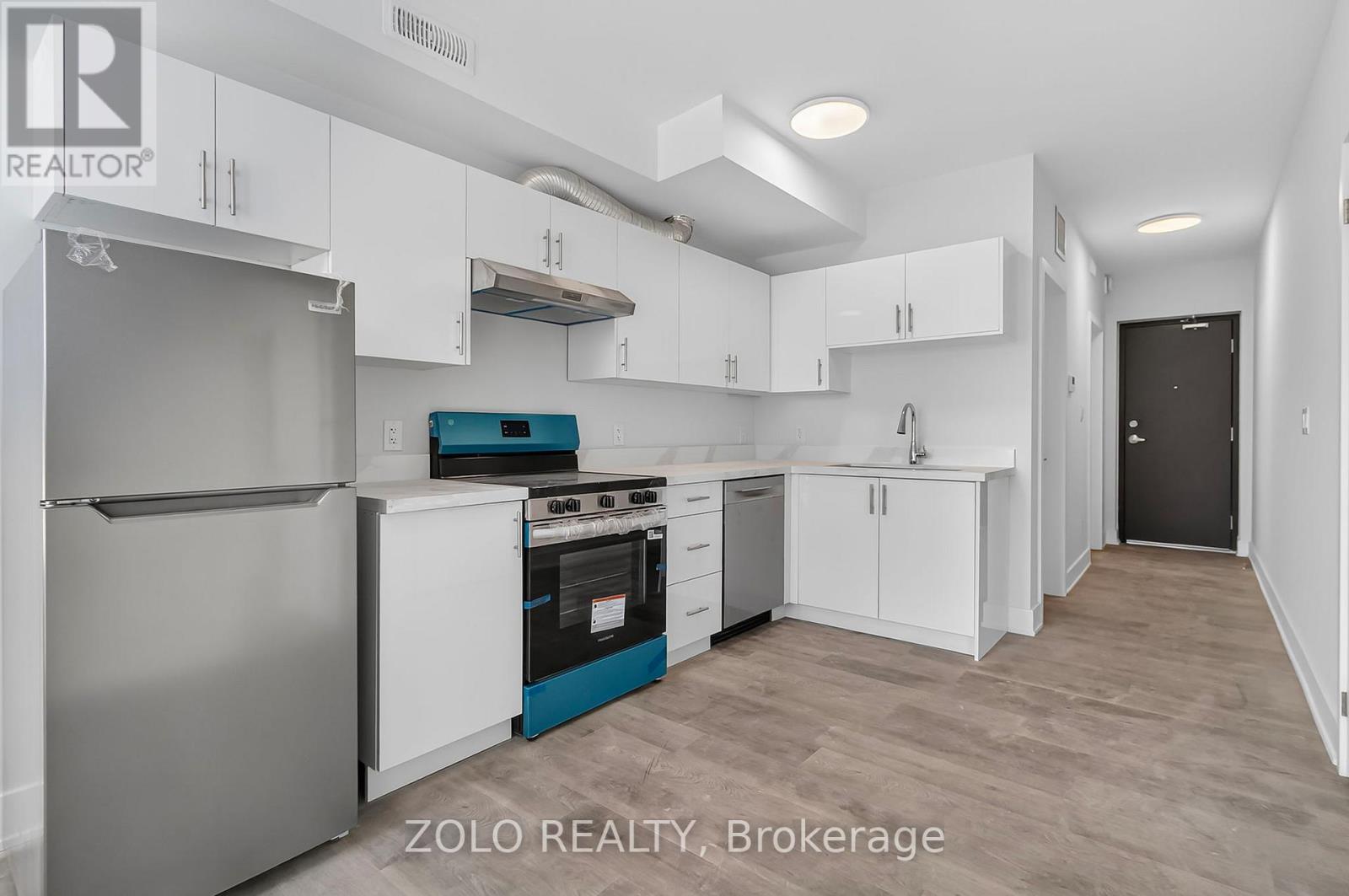 A kitchen with white cabinets and a stainless steel refrigerator.