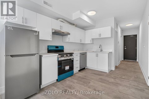A kitchen with white cabinets and a stainless steel refrigerator.