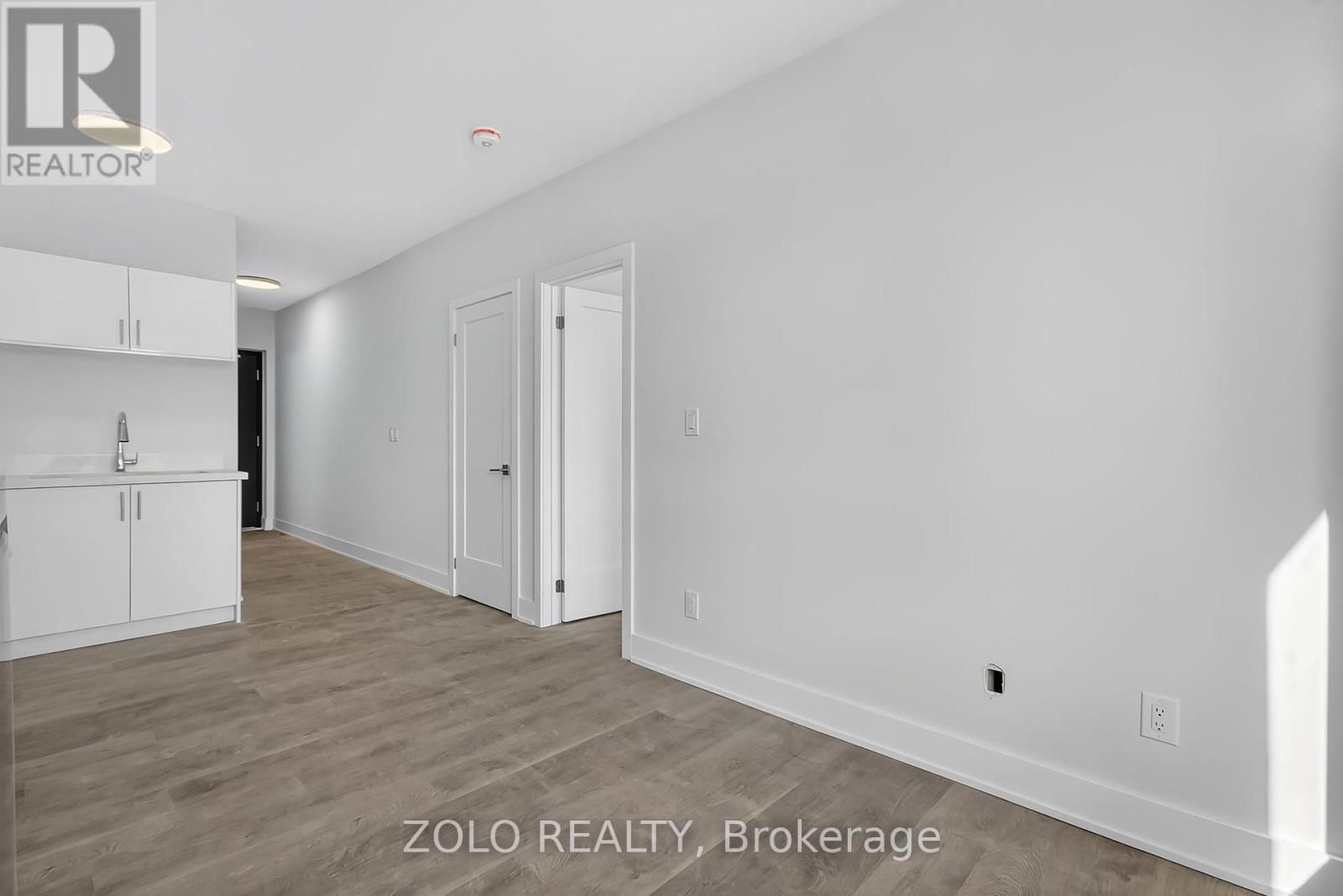 A realtor photo of a white room with a cabinet and a door.