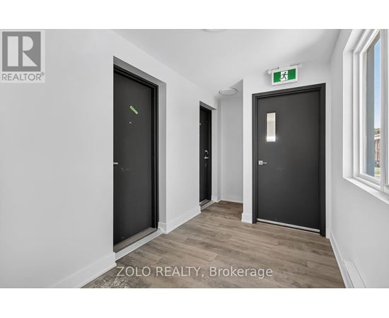 A hallway with two doors and a green exit sign above the right door.