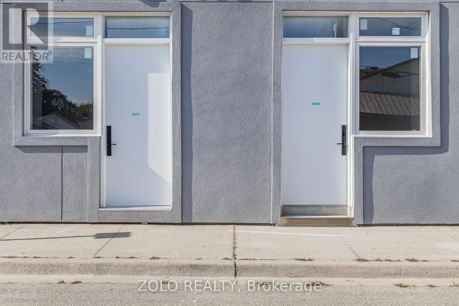 A grey building with two doors and windows.