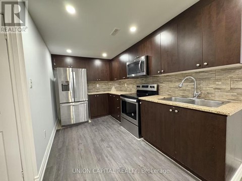 A kitchen with wooden cabinets and a stainless steel refrigerator.