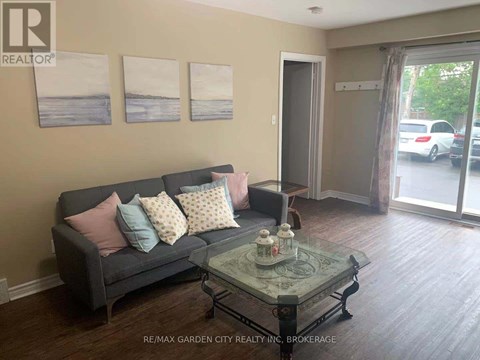 A living room with a grey couch and a glass coffee table.
