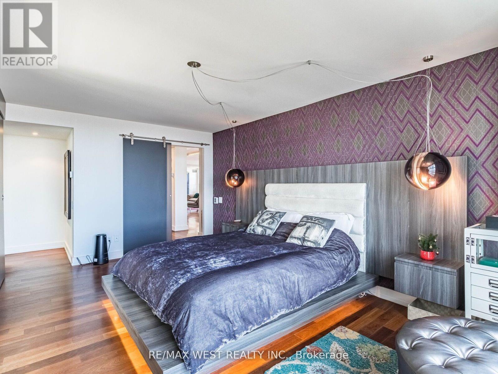A bedroom with a large bed and a purple wallpaper.