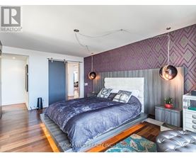 A bedroom with a large bed and a purple wallpaper.