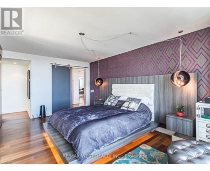 A bedroom with a large bed and a purple wallpaper.