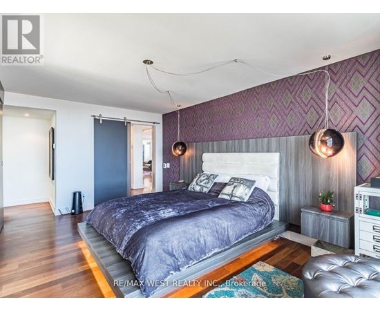 A bedroom with a large bed and a purple wallpaper.