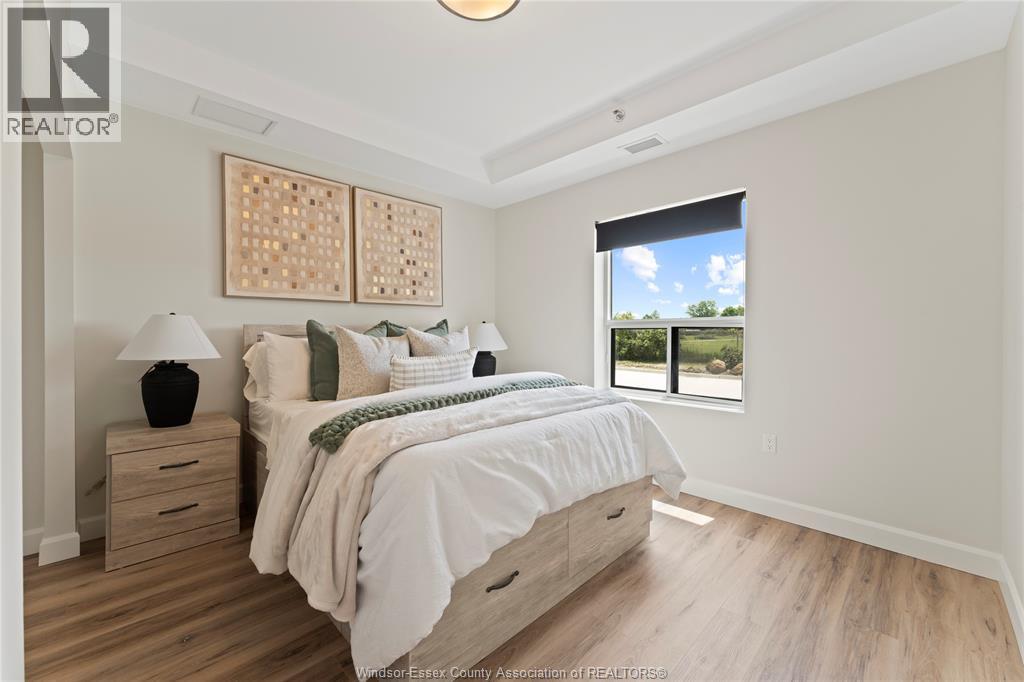 A bedroom with a large bed, wooden floors, and a window overlooking a green landscape.