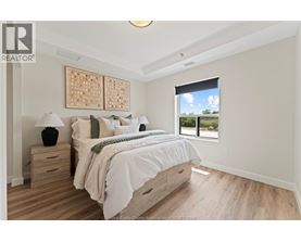 A bedroom with a large bed, wooden floors, and a window overlooking a green landscape.