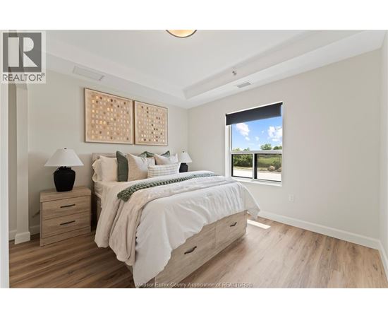 A bedroom with a large bed, wooden floors, and a window overlooking a green landscape.