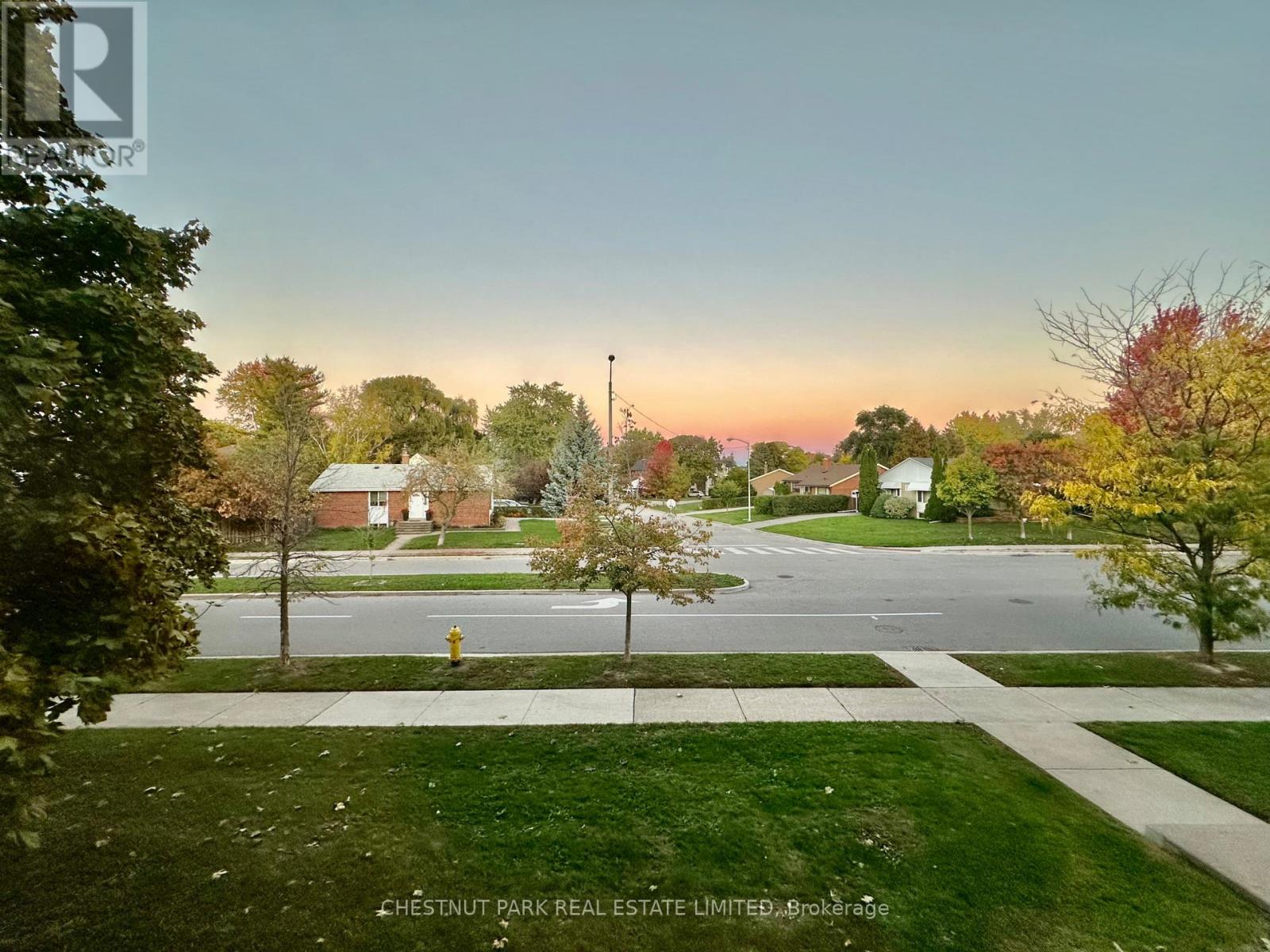 A residential street with houses and trees in the background.