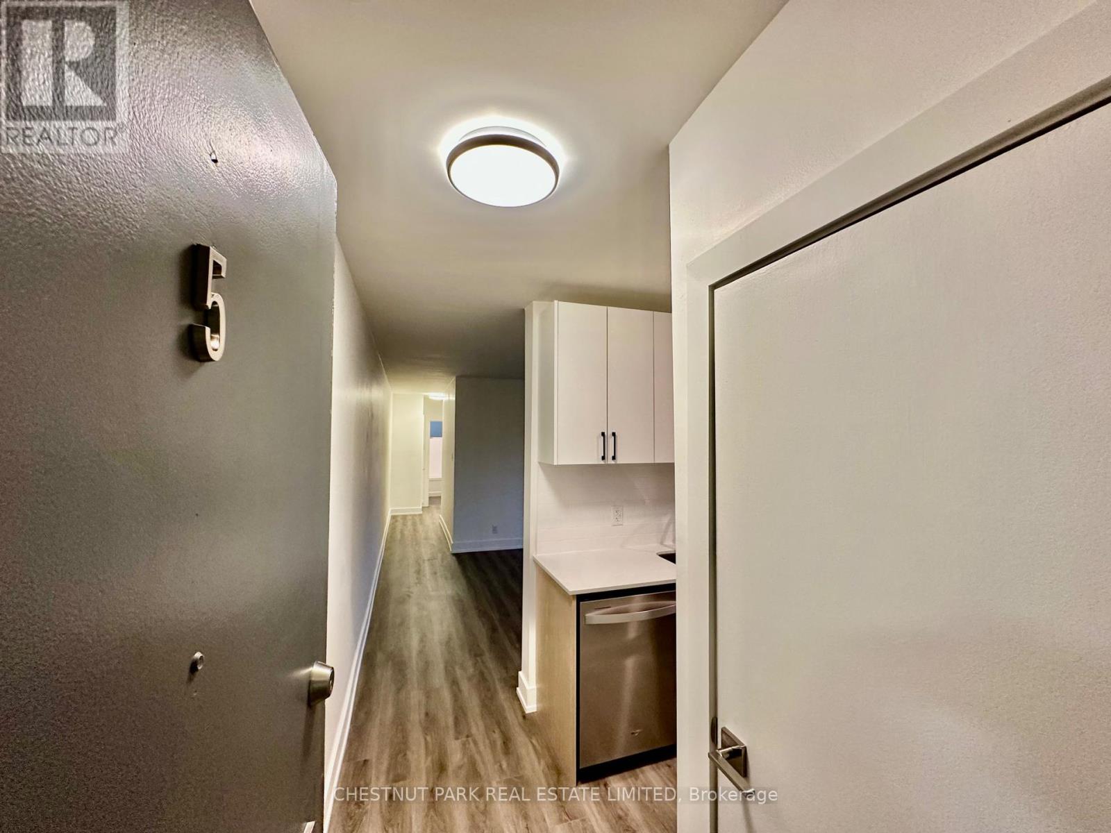 A hallway with a stainless steel refrigerator on the right.