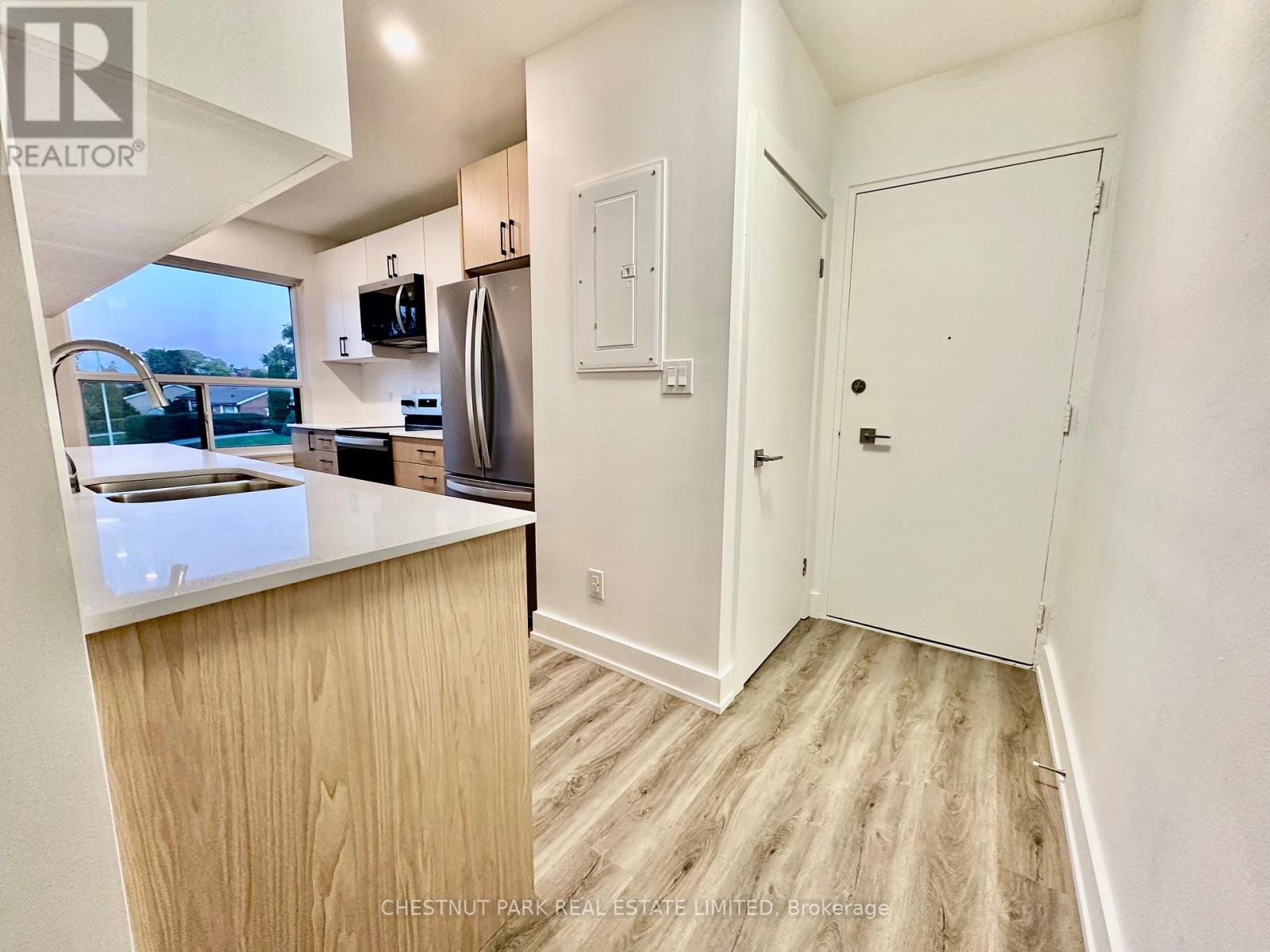 A kitchen with a refrigerator, microwave, and oven.