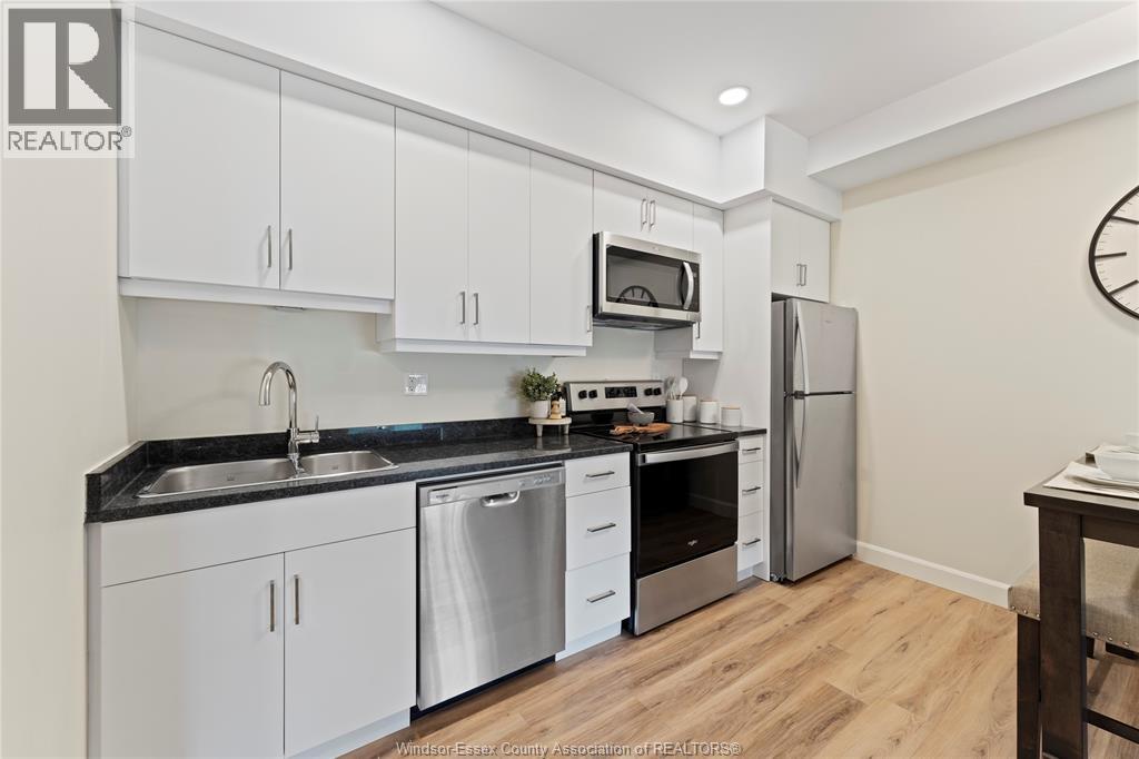 A kitchen with white cabinets and a black countertop.
