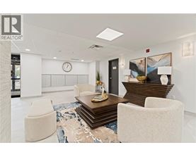 A modern office lobby with a wooden coffee table and two white chairs.