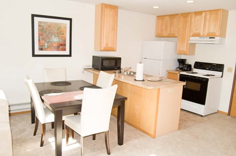 A kitchen with a table and chairs and a fridge.