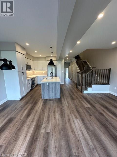 A spacious room with wooden flooring and a staircase.